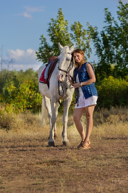 A garota de short abraça um cavalo branco