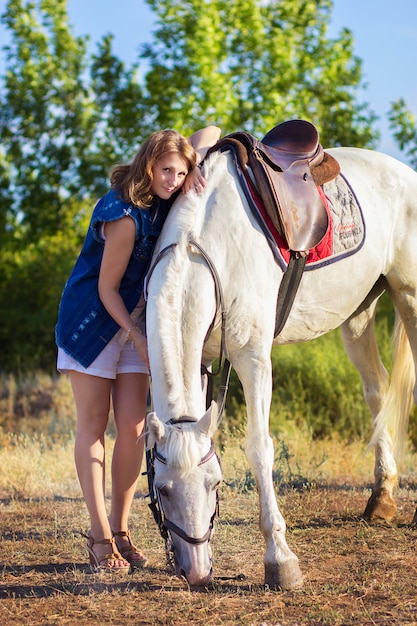 A garota de short abraça um cavalo branco