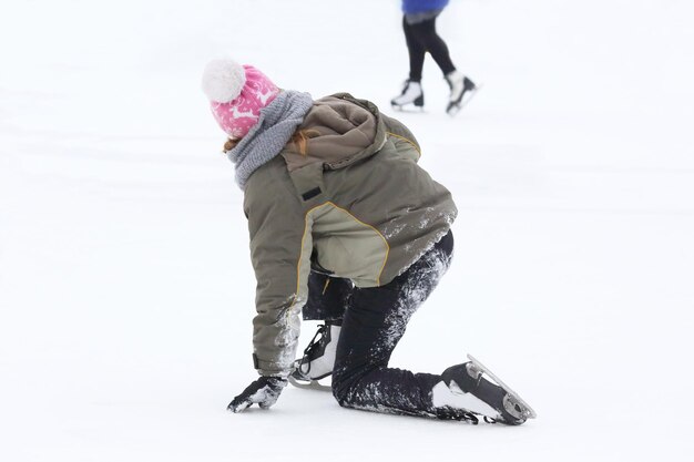 A garota dos patins se levanta após uma queda na pista de gelo