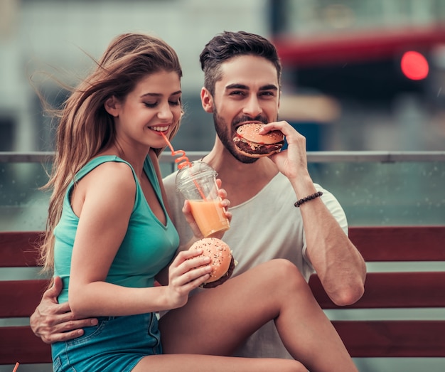 A garota e o cara estão sentados e comendo juntos.