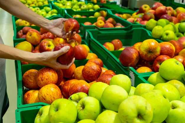 A garota escolhe maçãs no supermercado.