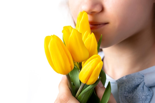 A garota está cheirando um buquê de tulipas amarelas segurando um buquê nas mãos