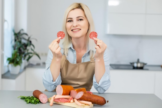 A garota está comendo salsicha. Um pedaço de salsicha. Sorriso e alegria. O conceito de negócio é o apelo da marca. Apetite