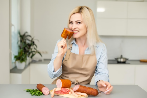 A garota está comendo salsicha. Um pedaço de salsicha. Sorriso e alegria. O conceito de negócio é o apelo da marca. Apetite