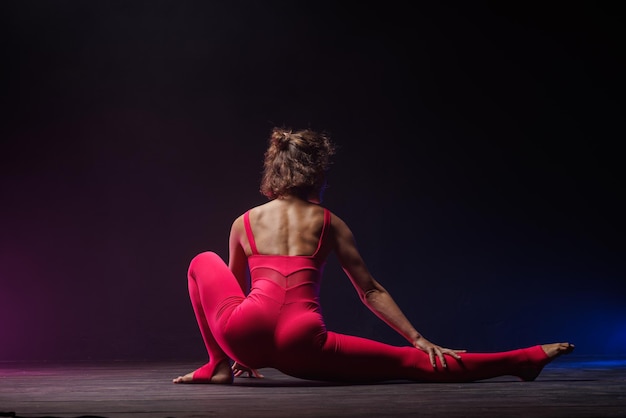 A garota está envolvida em esticar em um fundo escuro uma foto estilosa de fitness e ioga Copiar espaço