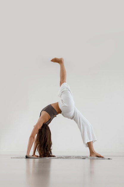 A garota está envolvida em yoga fica na pose da ponte com uma perna levantada Home Workouts