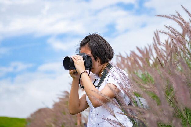 A garota está praticando fotografia profissional enquanto viaja em um belo prado.