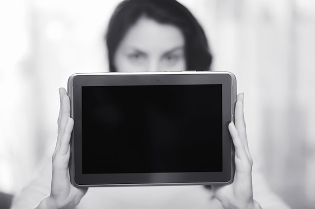 A garota está segurando o tablet. a garota tem um computador com uma tela nas mãos. as mãos seguram a tela com um espaço vazio.