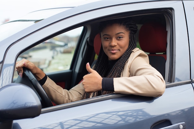 A garota feliz em um carro dirigindo, afro-americana