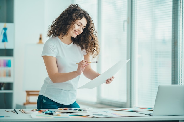 A garota feliz pintando um quadro na mesa