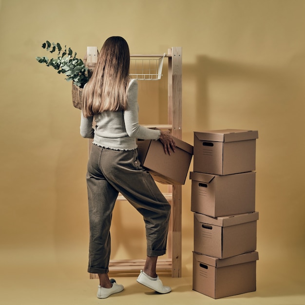 A garota inventa caixas de papel em uma prateleira de madeira. armazenamento e embalagem ecológicos.