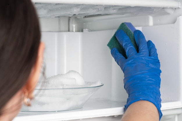 A garota lava o freezer. Limpar o refrigerador.