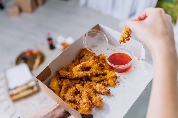 A garota mergulha nuggets de frango em um close-up de ketchup no fundo do chão e entrega fast-food.