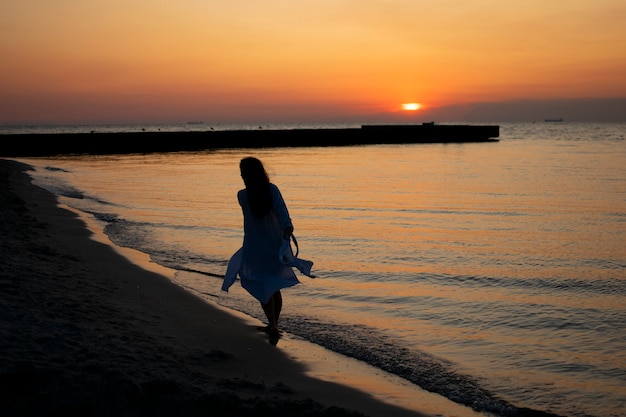 A garota na praia encontra o amanhecer, corre na areia.