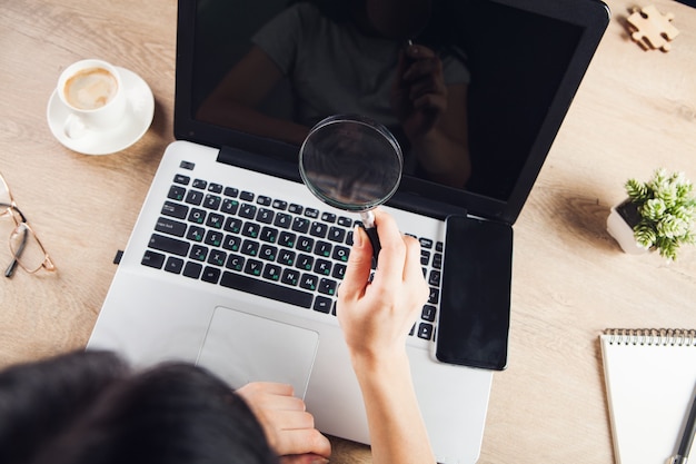 Foto a garota olha para o laptop com uma lupa