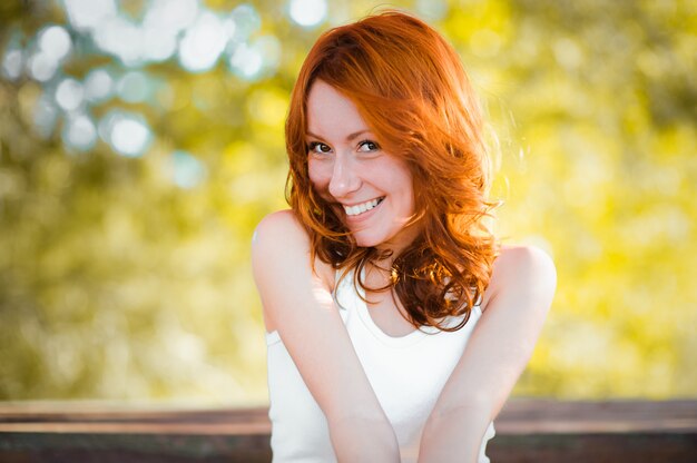 A garota ruiva sorri docemente, ri de volta. emoções reais. Uma mulher bonita com cabelos ruivos naturalmente encaracolados e um sorriso feliz e vibrante.