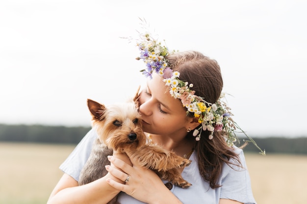 A garota segura um pequeno cachorro yorkie na natureza no verão. crianças e animais de estimação.