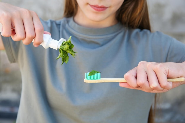 A garota segura uma escova de dentes com hortelã na mão Foco seletivo na escova de dentes de hortelã