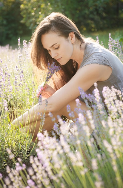 A garota senta no meio de um campo de lavanda