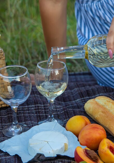 A garota serve vinho em um piquenique. foco seletivo. natureza.