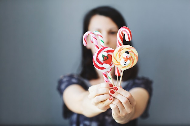 A garota tem doces de Natal coloridos nas mãos dela. Doces em primeiro plano. Conceito natal