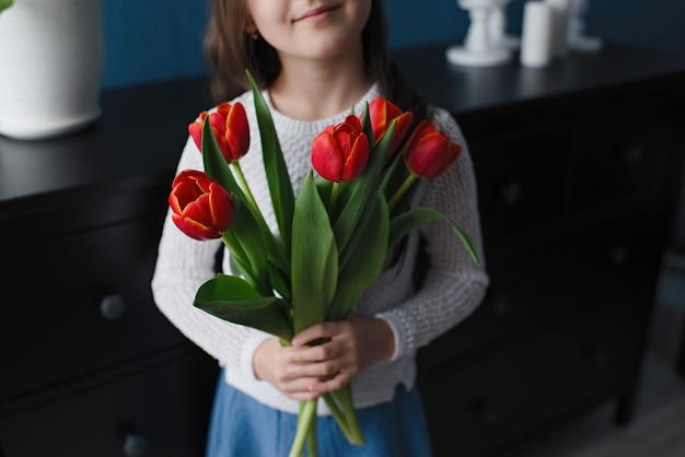 A garota tem flores vermelhas, tulipas nas mãos