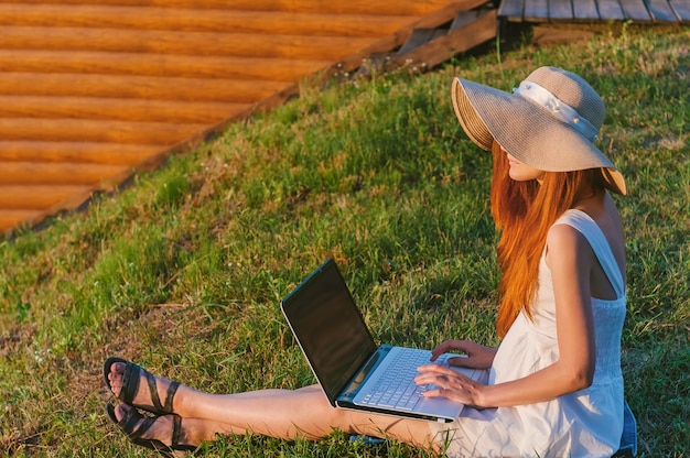 A garota trabalha para um laptop na natureza.