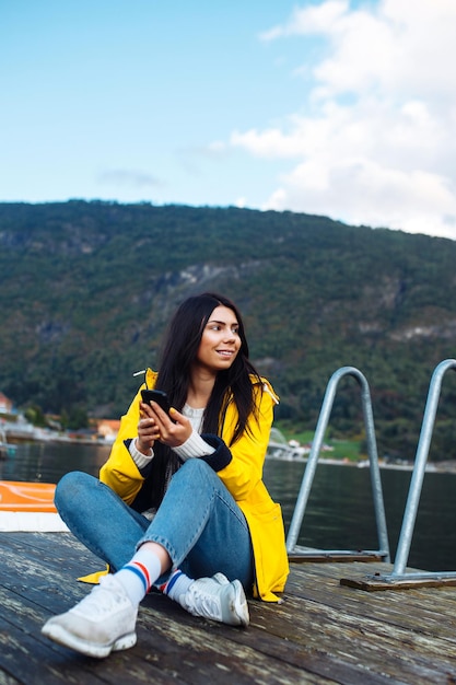 A garota turista tira uma foto no telefone à beira do lago na Noruega Jovem tira selfie