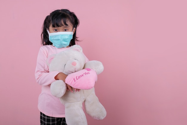 A garota usando uma máscara médica, traga um brinquedo