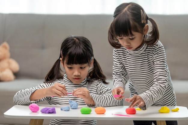 A garotinha está aprendendo a usar massinha colorida em uma sala bem iluminada