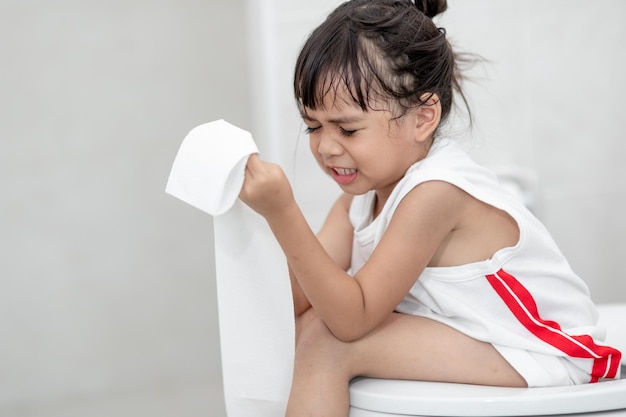 A garotinha está sentada no vaso sanitário sofrendo de constipação ou hemorroida