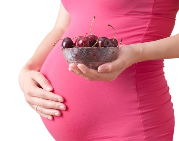 A grávida segura um prato com cereja. Isolado em um fundo branco