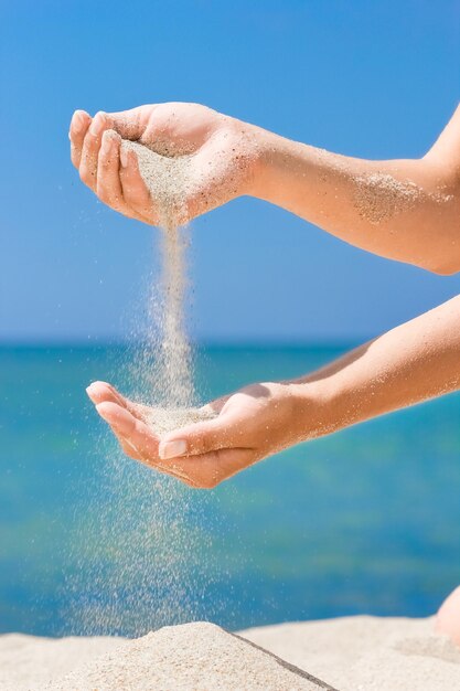 A Hände gießen Sand aus dem Meer auf die Natur auf einer Reise Urlaub am Meer Sandzeit vergeht