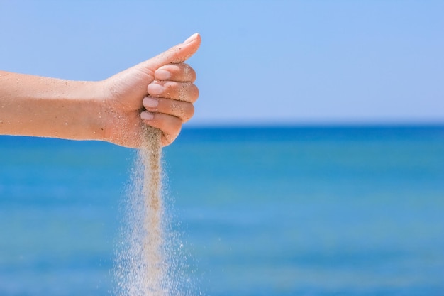 A Hände gießen Sand aus dem Meer auf die Natur auf einer Reise Urlaub am Meer Sandzeit vergeht