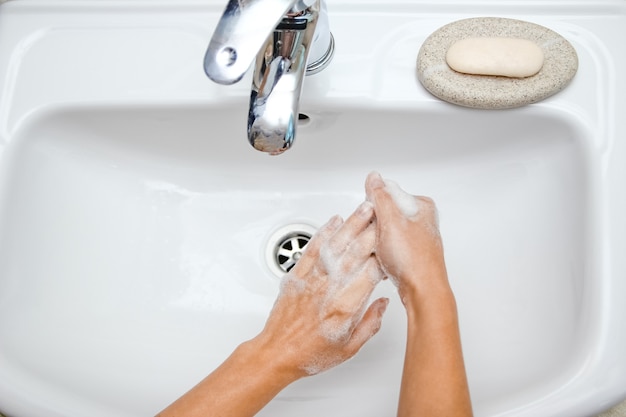 A Händewaschen mit Seife unter dem Wasserhahn mit Wasser