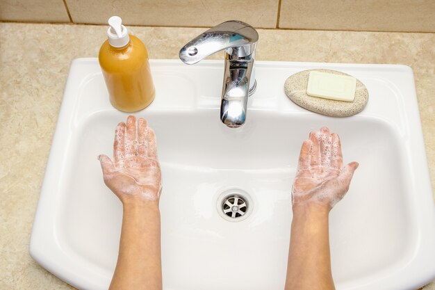 A Händewaschen mit Seife unter dem Wasserhahn mit Wasser