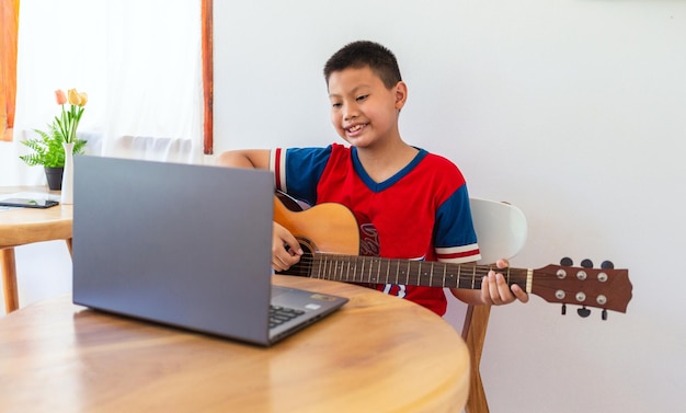 A história de um menino assistindo a um notebook enquanto se prepara para praticar violão em casa