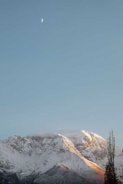 A ideia vertical da paisagem da natureza da neve tampou a cordilheira contra o céu azul claro.