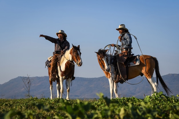 A imagem da ação do cowboy está montando um cavalo e segurando uma arma na mão.