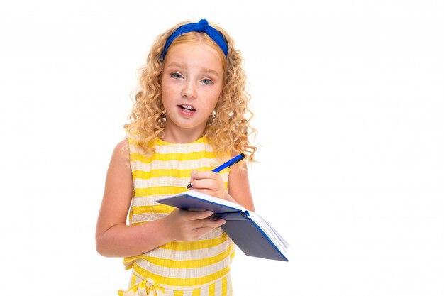 A imagem da criança feliz com cabelo encaracolado vermelho justo tem uma boa ideia e escreve-a no caderno isolado no fundo branco