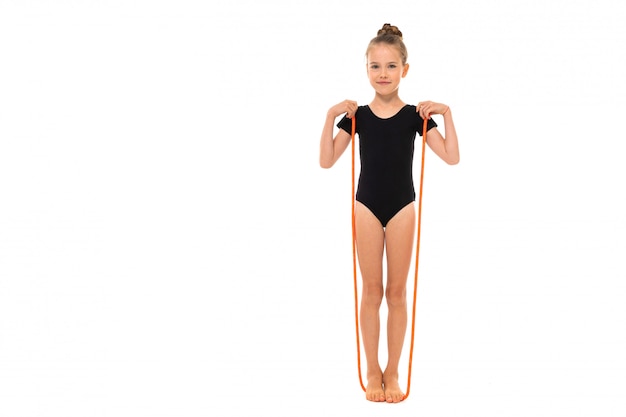 A imagem da ginasta da menina no trico preto na altura completa está em uma corda de salto isolada em um fundo branco