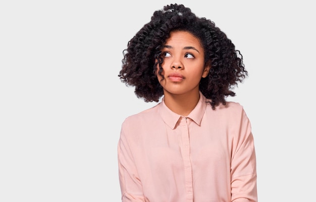 A imagem da mulher afro-americana pensativa tem expressão de pensamento olhando para o espaço em branco da cópia A mulher de pele escura duvidosa não pode fazer a escolha questionou a expressão isolada no branco