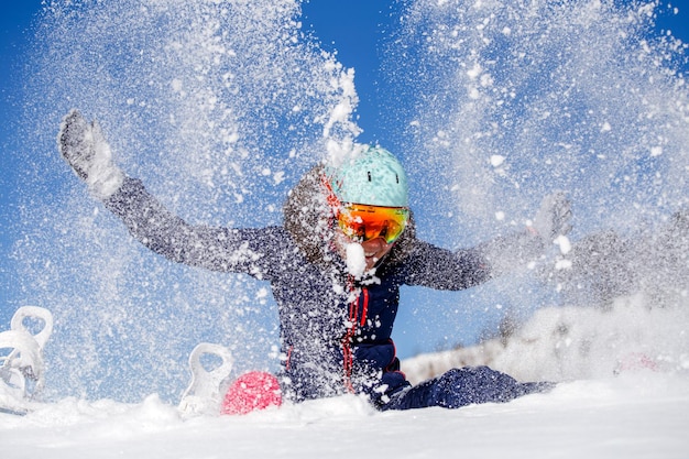 A imagem da mulher do atleta que senta-se no monte de neve joga a neve