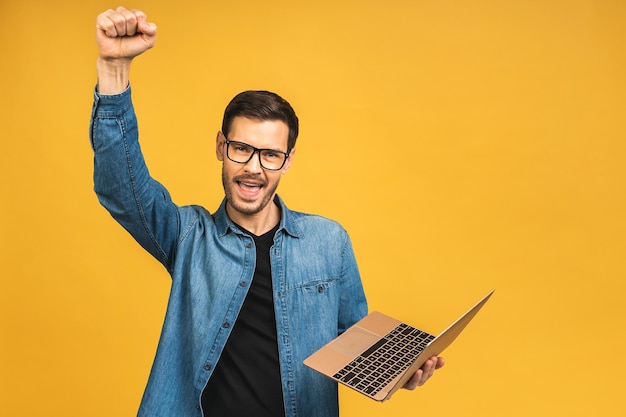 Foto a imagem de um jovem feliz e animado usando um laptop faz um gesto de vencedor