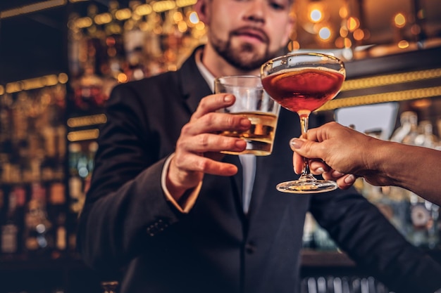 A imagem recortada de um casal atraente está passando a noite em um ambiente romântico, bebendo vinho no balcão do bar.