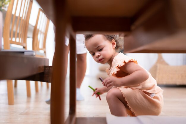 A imaginação de uma criança pequena é representada através de desenhos a lápis de cor com a mãe supervisionando atentamente na sala de estar da casa