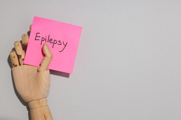 Foto a inscrição epilepsia em um pedaço de papel em uma mão de madeira