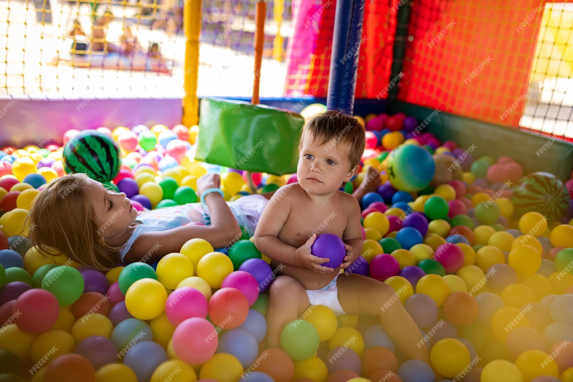 irmão com irmã jogando na piscina de bolinhas coloridas