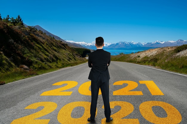 A jornada de Ano Novo de 2021 e o conceito de visão de futuro. Empresário, viajando na estrada rodoviária que conduz à celebração do feliz ano novo no início de 2021 para um começo novo e bem sucedido.