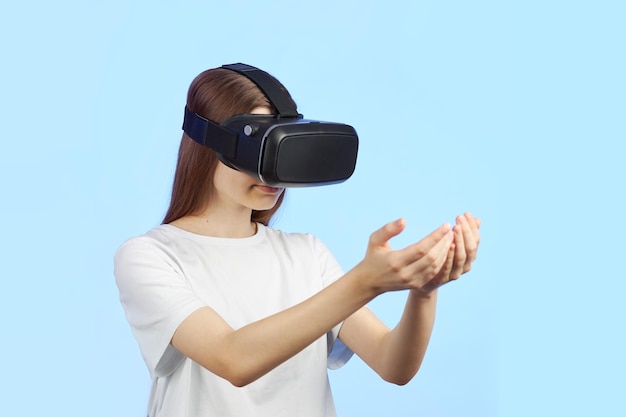A jovem adolescente em um capacete de realidade virtual segura um objeto tridimensional em suas mãos